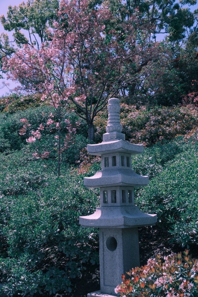 a tall stone tower sitting in the middle of a garden